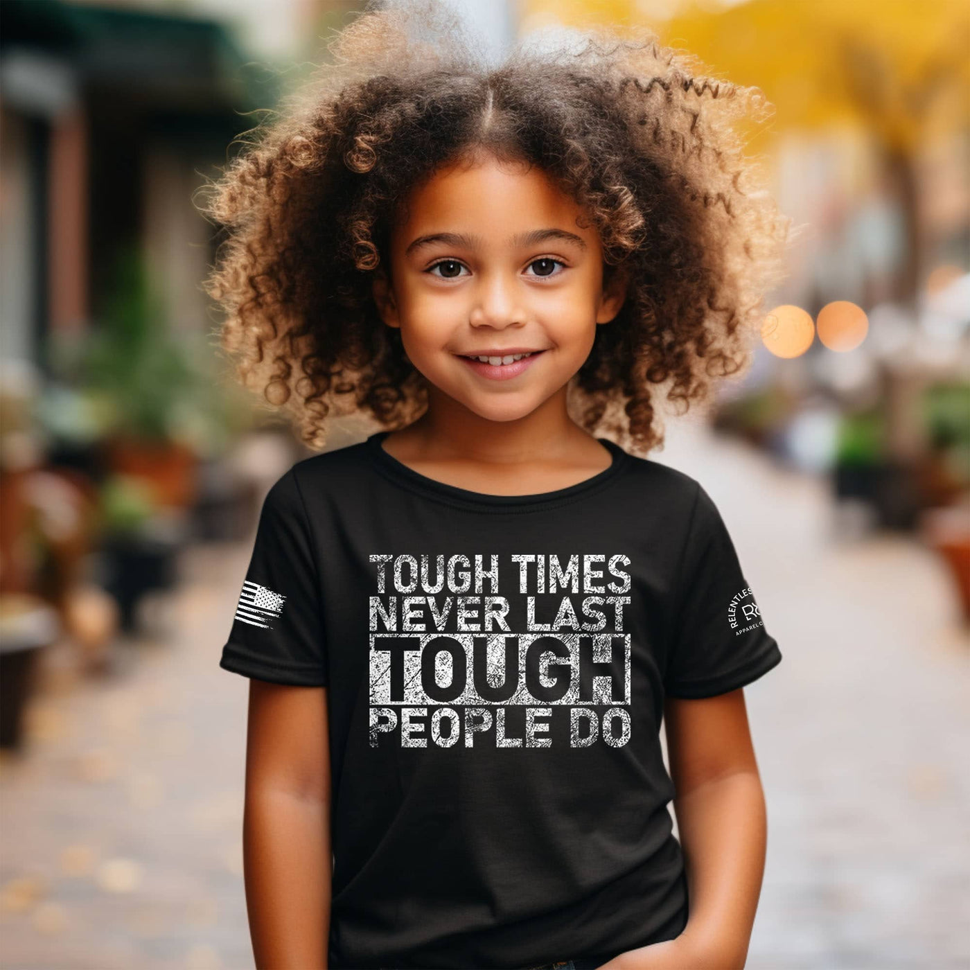 Child wearing a black t-shirt with motivational quote in an outdoor setting
