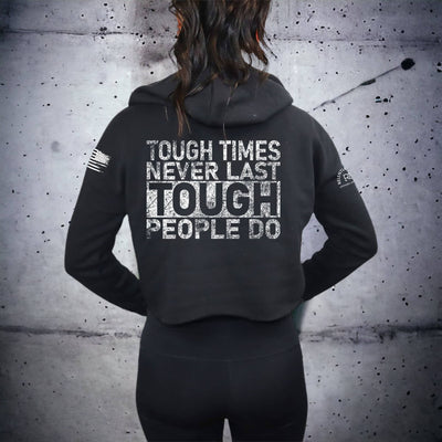 Person wearing a black hoodie with motivational text on the back against a textured wall.