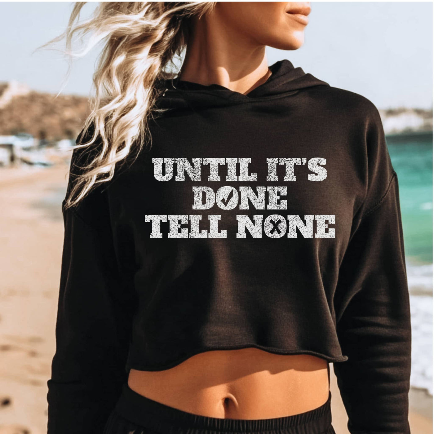 Person wearing a black hoodie with text on a beach