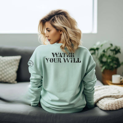 Woman wearing a light green sweatshirt with text on the back, sitting on a couch in a living room.