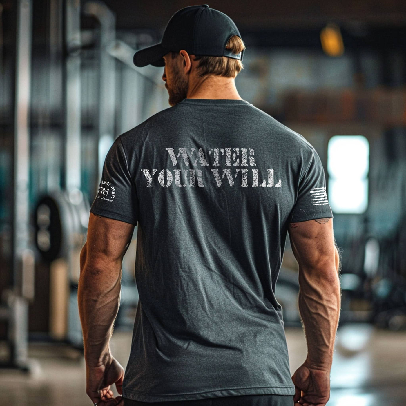 Man wearing a dark gray t-shirt with 'WATER YOUR WILL' text, standing in an indoor setting.