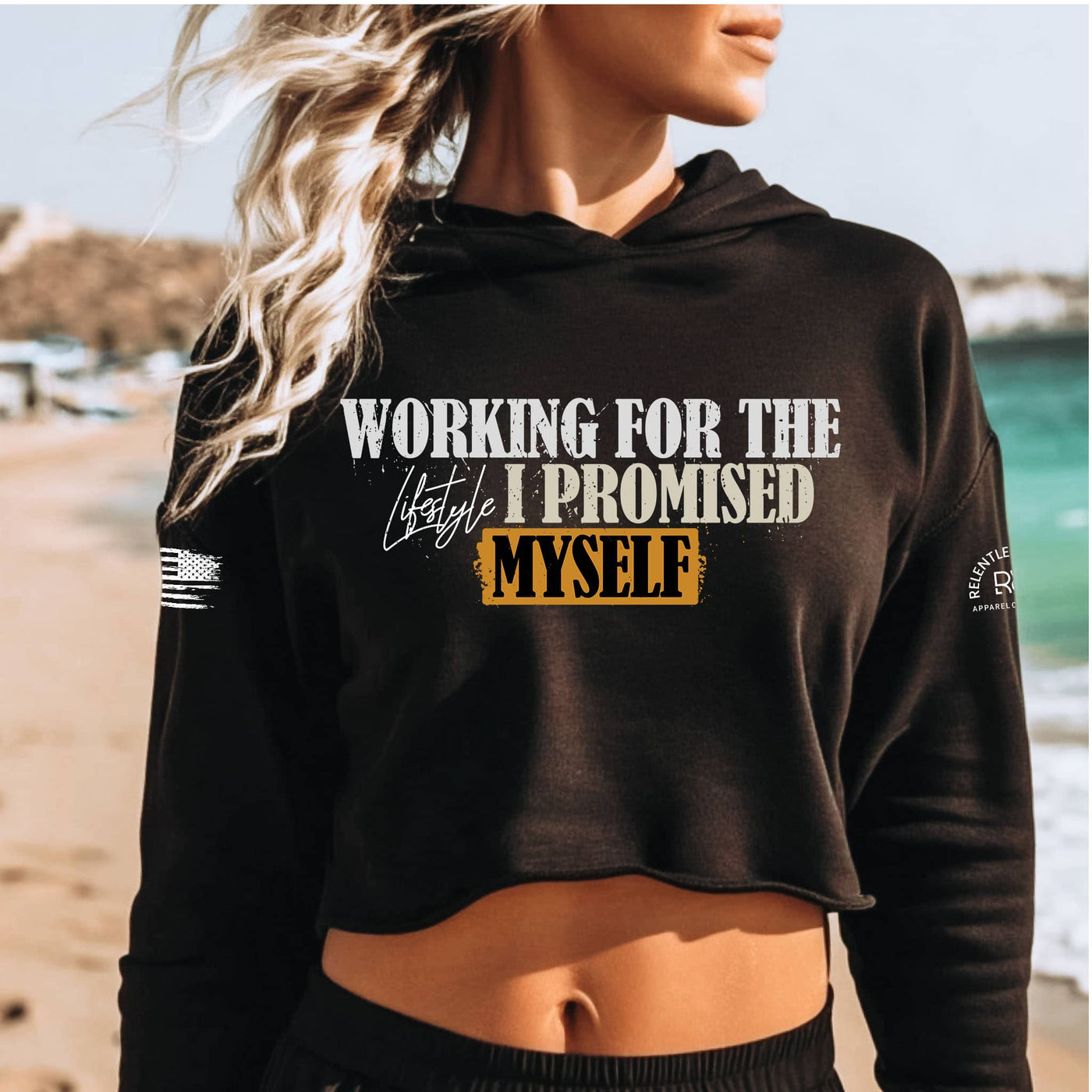Person wearing a black hoodie with text on a beach