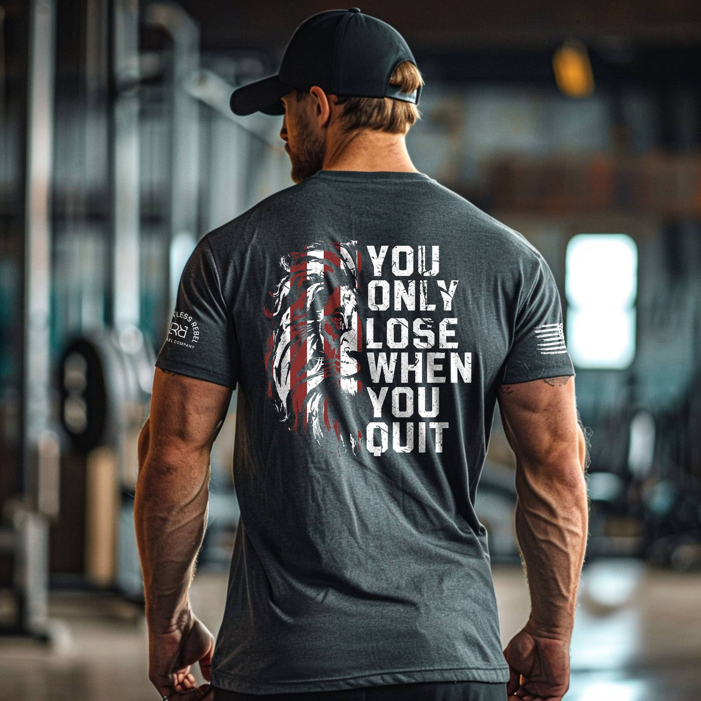 Man wearing a motivational t-shirt with an American flag design and text in a gym setting