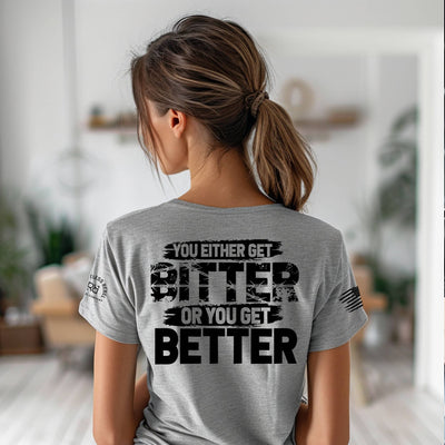 Person wearing a gray t-shirt with a motivational quote in a blurred indoor setting