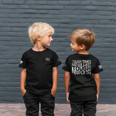 Two children wearing black t-shirts with text and logos against a brick wall.