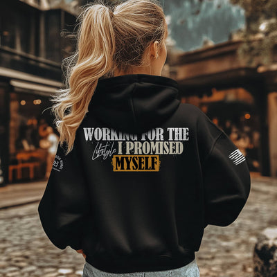 Person wearing a black hoodie with text on the back, standing outdoors.