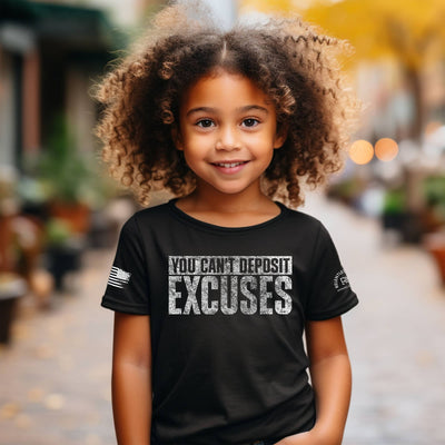 Child wearing a black t-shirt with motivational text, standing outdoors.