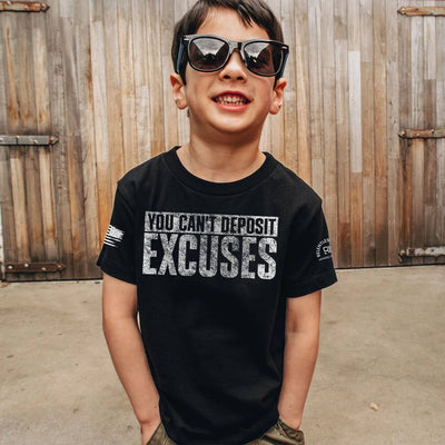 Child wearing a black t-shirt with motivational text in front of wooden shutters.