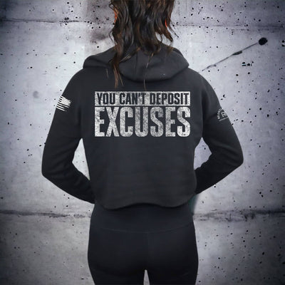 Person wearing a black hoodie with motivational text on the back against a textured wall.