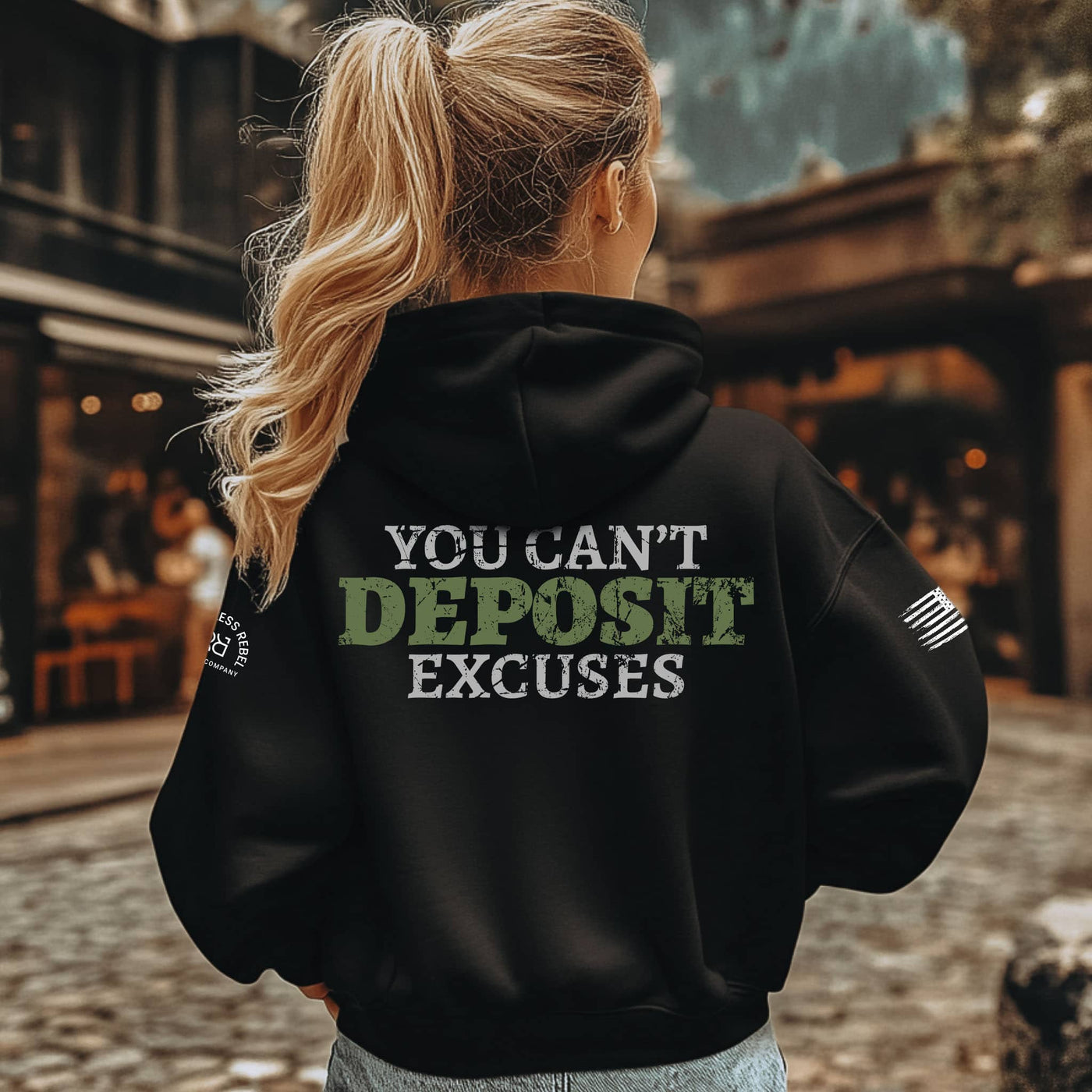 Person wearing a black hoodie with motivational text outdoors