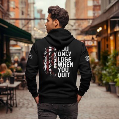 Man wearing a black hoodie with motivational text on the back in an urban setting