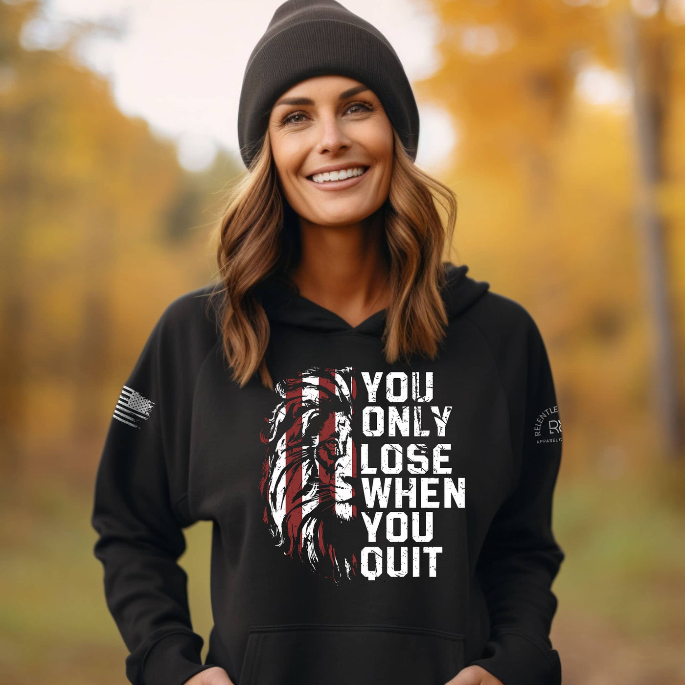 Woman wearing a black hoodie with a motivational quote in an autumn setting